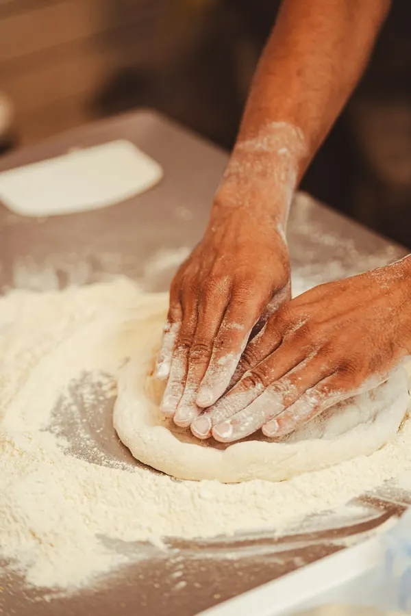 Pizzaiolo wyrabia ciasto na pizzę