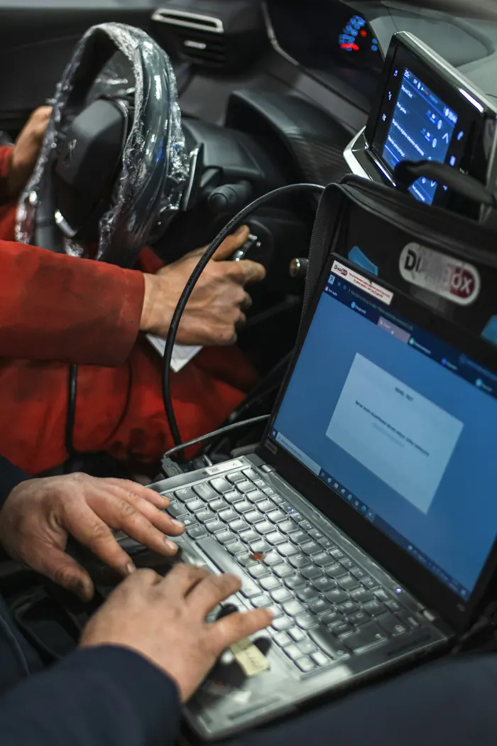 Technik z laptopem podczas diagnostyki komputerowej auta